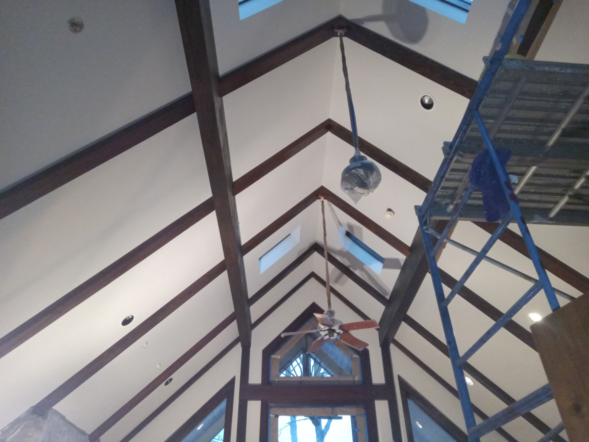 Cathedral chevron ceiling beams between cream-painted panels