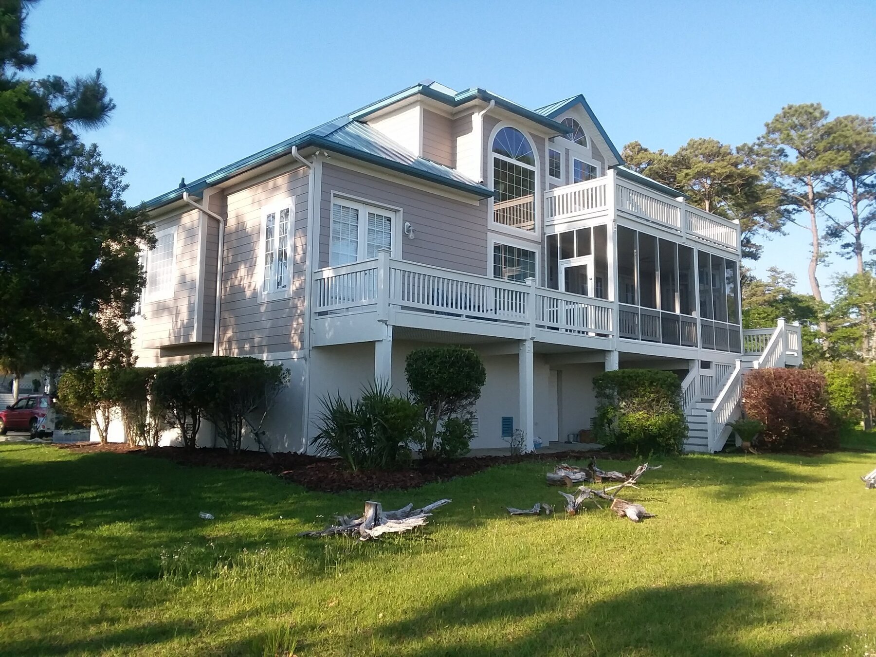 Large cream-colored coastal home with wraparound deck