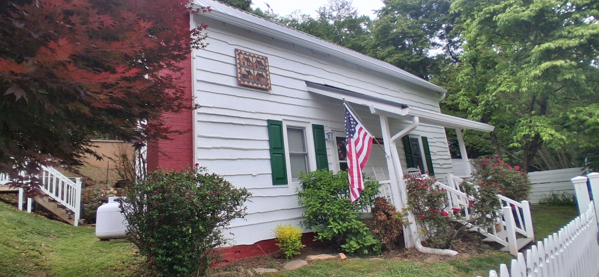 White cottage exterior repaint in progress with red brick chimney and US flag
